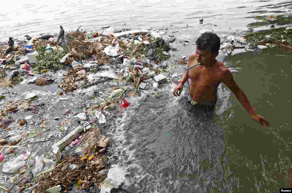 Seorang pria menggosok gigi di sungai Ganga yang penuh sampah di Kolkata, India.