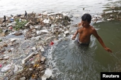 A man brushes his teeth as he stands in the polluted water of river Ganga in Kolkata, India May 23, 2017.