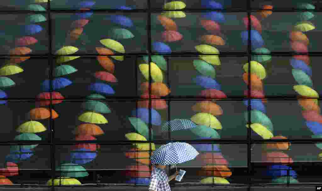 A man walks by window reflections of sun umbrellas used in an art display in a courtyard at the Geumcheon government building in Seoul, South Korea.