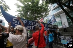Demonstrators, carrying a boat, rally outside the Chinese Consulate at the financial district of Makati city, east of Manila, Philippines, to protest China's reclamations of disputed islands off South China Sea, July 3, 2015. The reclamations have straine