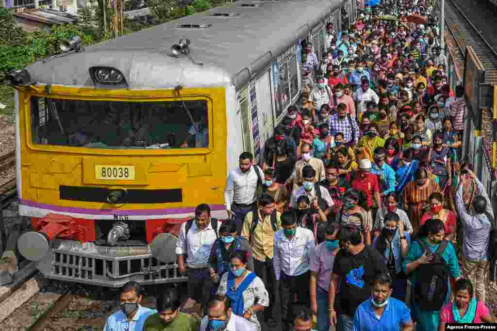 Commuters disembark a suburban local train in Kolkata as the train services resumed normalcy after COVID-19 restrictions were lifted.