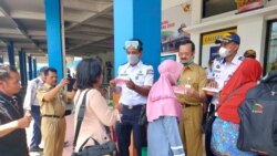 Petugas membagi-bagikan masker bagi pemudik untuk mencegah penyebaran virus corona (VOA/Yudha).