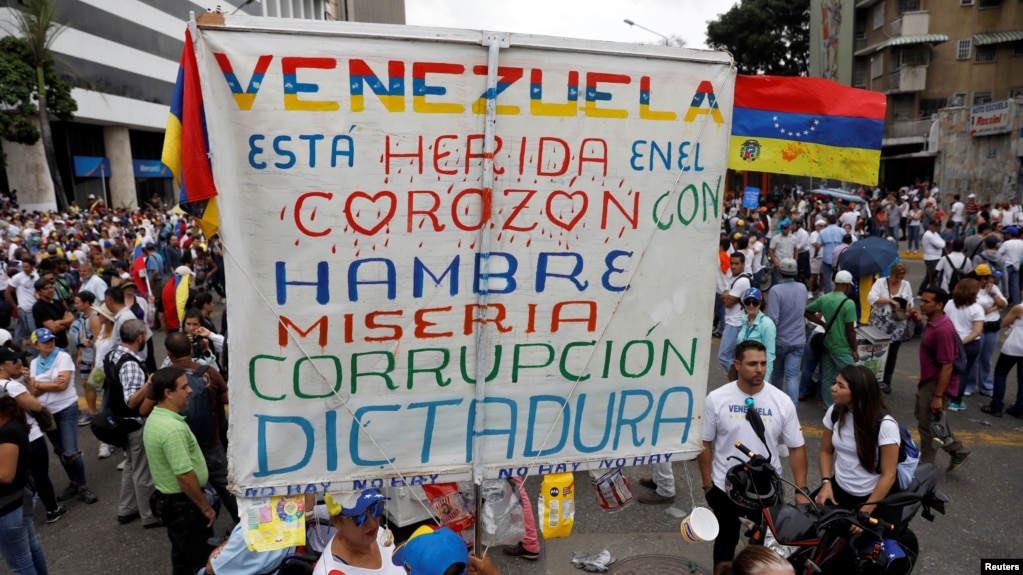 FILE - Opposition supporters rally against President Nicolas Maduro carrying a sign that reads "Venezuela is wounded in the heart with hunger, misery, corruption and dictatorship," in Caracas, Venezuela, May 10, 2017.