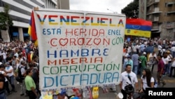 FILE - Opposition supporters rally against President Nicolas Maduro carrying a sign that reads "Venezuela is wounded in the heart with hunger, misery, corruption and dictatorship," in Caracas, Venezuela, May 10, 2017.