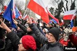 Demonstrators display Polish and European Union flags during the third day of a protest outside the Parliament building in Warsaw, Dec. 18, 2016.