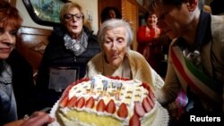 Emma Morano, yang ditetapkan sebagai orang tertua di dunia dan yang terakhir yang lahir tahun 1800an, meniup lilin ulang tahun ke-117 di Verbania, Italia utara (29/11). (Reuters/Alessandro Garofalo)