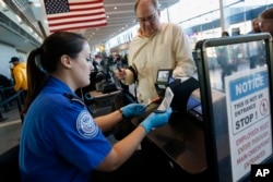 Transportation Security Administration officer Darby Finch checks boarding passes and identification at Logan International Airport in Boston, Dec. 23, 2018.