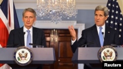 U.S. Secretary of State John Kerry (R) makes remarks as Britain's Foreign Secretary Philip Hammond looks on, during a press availability at the State Department in Washington, Oct. 8, 2014.