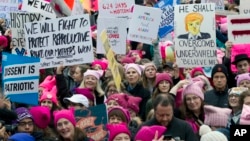 FILE - Women with pink hats and signs protested on the first full day of Donald Trump's presidency, Jan. 21, 2017 in Washington. Discussions about the Women’s March on Washington and other locations sent many people to look up “feminism.”