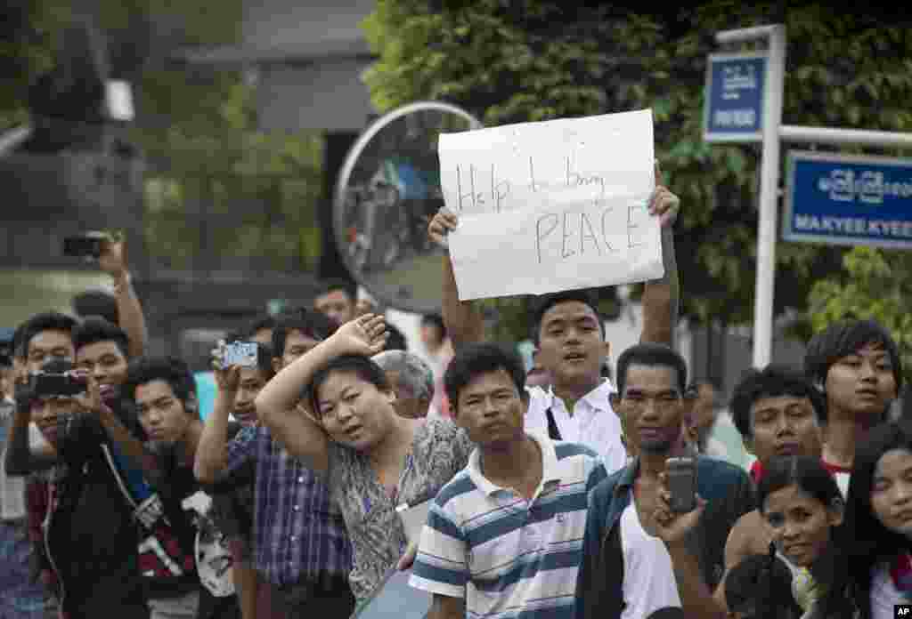 2012年11月19日，人们排列街头欢迎美国总统奥巴马访问缅甸，一位男士举着&ldquo;帮助实现和平&rdquo;的标语牌。