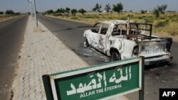 Une camionnette de patrouille de police brûlée reste abandonnée sur le bord d'une route déserte à Damaturu, dans l'État de Yobe, au Nigeria le 7 novembre 2011.