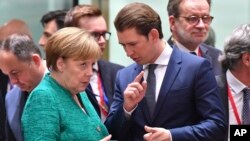 German Chancellor Angela Merkel, left, speaks with Austrian Chancellor Sebastian Kurz during a round table meeting at an EU summit in Brussels, Belgium, June 28, 2018. 
