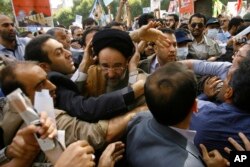 Escorted by his bodyguards, reformist former Iranian President Mohammad Khatami, center, is attacked by hard-liners as he attends a Quds Day rally, in Tehran, Sept. 18, 2009.