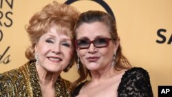 Debbie Reynolds, winner of the Screen Actors Guild lifetime award (left) and Carrie Fisher pose in the press room at the 21st annual Screen Actors Guild Awards at the Shrine Auditorium, Jan. 25, 2015, in Los Angeles. 