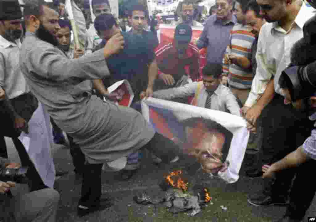 A Syrian protester kicks a burning picture of Syrian President Bashar Assad during a protest in front of the Arab League headquarters in Cairo, Egypt, Saturday, Nov.12, 2011 where an Arab League emergency session on Syria is taking place to discuss the co