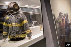 The helmet and turnout coat, left, belonging to firefighter Jonathan Ielpi and the badge and gun belonging to police officer John Perry, who both died during the terrorist attacks on the World Trade Center, are on display at the 9/11 Tribute Museum in New