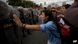 University students confront a line of Venezuelan National Guard officers in riot gear during a protest outside of the Supreme Court in Caracas, Venezuela, March 31, 2017.