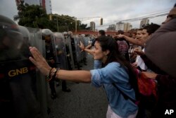 University students confront a line of Venezuelan National Guard officers in riot gear during a protest outside of the Supreme Court in Caracas, March 31, 2017.