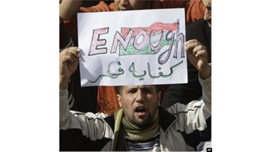 A Libyan protester holds up a sign against Libyan Leader Moammar Gadhafi during a demonstration, in Tobruk, Libya, February 23, 2011