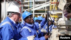 FILE - Ghana's President John Atta Mills turns on the valve to allow the first barrel of crude to flow from the Jubilee offshore oil field.