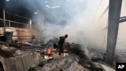 FILE - A worker looks for survivors under the rubble of a food factory hit by Saudi-led airstrikes in Sana'a, Yemen, Aug. 9, 2016. 