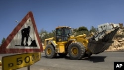 Workers drive ground-moving equipment at a construction site in the Jewish settlement of Revava, near the West Bank city of Nablus (File Photo)