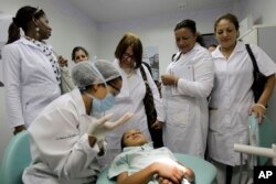 FILE - In this Aug. 30, 2013 file photo, Cuban doctors observe a dental procedure during a a training session at a health clinic in Brasilia, Brazil.