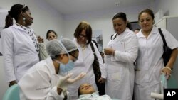 FILE - Cuban doctors observe a dental procedure during a a training session at a health clinic in Brasilia, Brazil, Aug. 30, 2013.