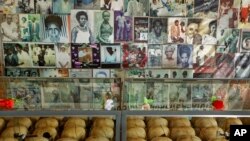 Flowers are laid on top of a glass case containing the skulls of some of those who were slaughtered as they sought refuge in the church, next to photographs of some of them, kept as a memorial to the thousands killed in and around the Catholic church during the 1994 genocide.