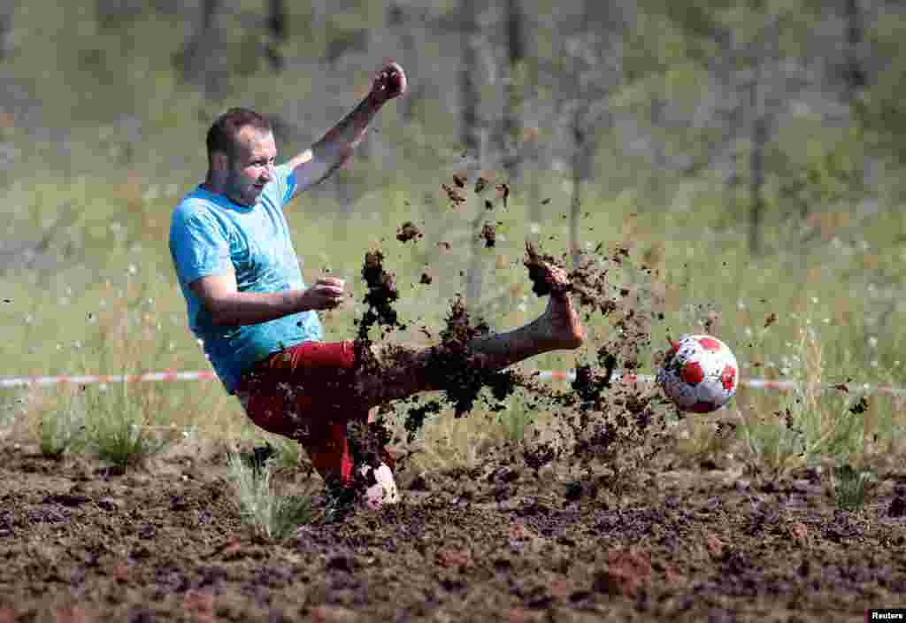 A soccer enthusiast kicks a ball while competing in the Swamp Football Cup of Russia in the village of Pogi in Leningrad Region, Russia, June 16, 2018.