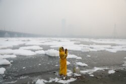 Seorang perempuan berdoa di tepi sungai Yamuna di New Delhi, pada pagi yang berkabut, 8 November 2021. (REUTERS/Anushree)