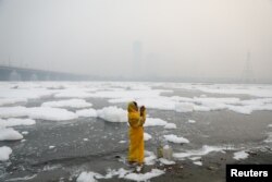 Seorang perempuan berdoa di tepi sungai Yamuna di New Delhi, pada pagi yang berkabut, 8 November 2021. (REUTERS/Anushree)