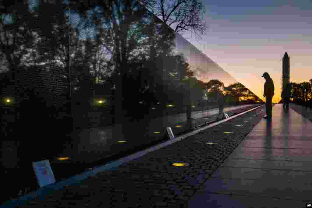 A visitor at the Vietnam War Memorial in Washington, D.C. passes early in the morning on Veterans Day, Nov., 11, 2013, to look at the names inscribed on the wall.