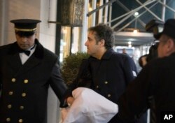 Michael Cohen arrives at his home in New York with his left arm in a sling supported by a pillow, Jan. 18, 2019.