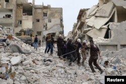 Civil defense members work at a site hit at dawn by an airstrike in the rebel-controlled town of Ariha in Idlib province, Syria, Feb. 27, 2017.