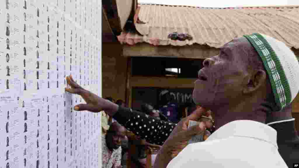 Un homme cherche son nom sur une liste avant de s&#39;enregistrer et de voter en plaçant son bulletin de vote dans l&#39;urne plus tard dans la journée à Lagos, au Nigeria, samedi 28 mars 2015.