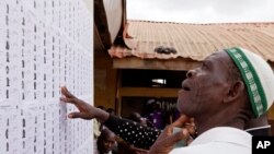 Un homme cherche son nom sur une liste avant de s'enregistrer et de voter en plaçant son bulletin de vote dans l'urne plus tard dans la journée à Lagos, au Nigeria, samedi 28 mars 2015.