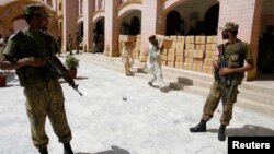 Pakistani soldiers stand guard outside a district court as election commission workers carry election materials in Hyderabad, May 8, 2013.