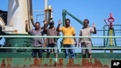 FILE - Crew members wave from aboard the Aris 13 oil tanker, which was released by pirates after negotiations by officials and local elders in Somalia's semiautonomous northeastern state of Puntland, March 19, 2017.