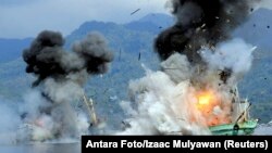 Two foreign-flagged fishing boats registered in Papua New Guinea are destroyed by the Indonesian Navy after they were seized earlier for supposedly illegal fishing off the coast of Ambon, Maluku, Dec. 21, 2014.
