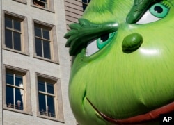 FILE - The Grinch balloon passes by windows of a building on Central Park West during Macy's Thanksgiving Day Parade in New York, Nov. 23, 2017.