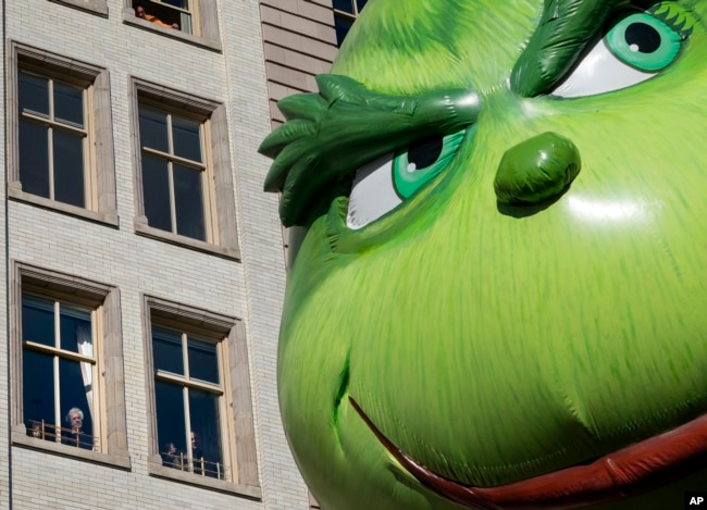 FILE - The Grinch balloon passes by windows of a building on Central Park West during Macy's Thanksgiving Day Parade in New York, Nov. 23, 2017.