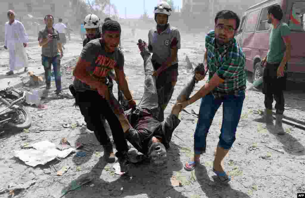 Syrian rescue workers and civilians evacuate a man in the Maadi district of eastern Aleppo after regime aircrafts reportedly dropped explosive-packed barrel bombs, Aug. 27, 2016.