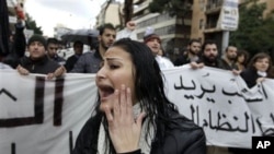 A woman shouts slogans as protesters behind her carry a banner condemning Lebanon's current sectarian system of government, Beirut, February 27, 2011