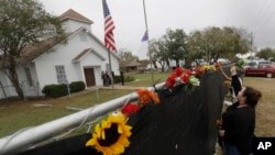 Rachel Vasquez places flowers in a fence for the victims of the shooting outside of the Sutherland Springs Baptist Church following a service held at a temporary site, Nov. 12, 2017, in Sutherland Springs, Texas.