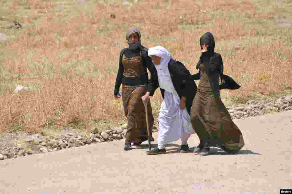 Displaced families from the minority Yazidi sect, fleeing the violence, walk on the outskirts of Sinjar, west of Mosul, Aug. 5, 2014.