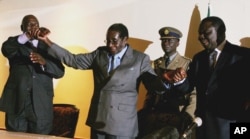 Zimbabwean President Robert Mugabe, centre, holds the hands of Morgan Tsvangirai, leader of the main opposition party, right, and Arthur Mutambara, leader of the other faction of the opposition party, at the signing of a memorandum of understanding betwee