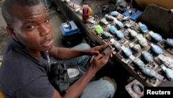 FILE - Jamil Idriss charges 50 naira ($0.33) to recharge phone batteries using rows of three-pin sockets nailed to a plank of wood and plugged into a diesel generator in the Obalende district of Lagos, Nigeria, May 20, 2010. 