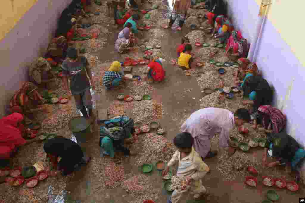Warga Pakistan mengupas udang pada peternakan udang di Karachi.