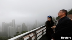Mainland Chinese visitors look at the foggy skyline of Hong Kong island from the Peak in Hong Kong, Feb. 24, 2015. 